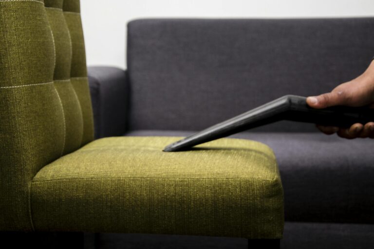 Close-up of a person vacuuming a modern sofa chair indoors, highlighting cleaning service.